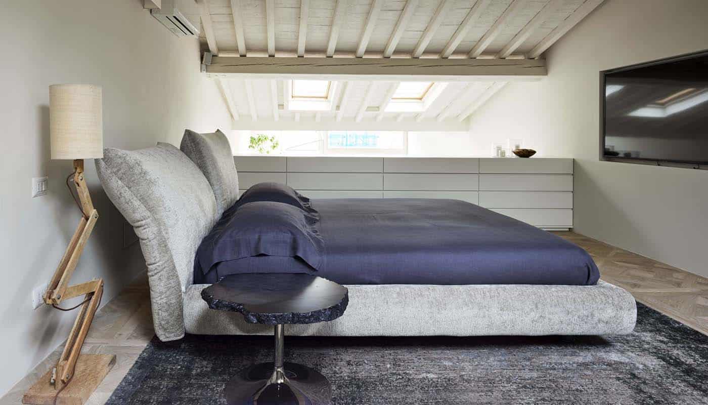 luxe Italiaans designbed van het merk Edra, in een bruine stof, bekend als het "Stand by Me" bed, dat wordt verkocht bij Noctum in Rotterdam. Het bed wordt gekenmerkt door verstelbare slimme kussens, die comfort en veelzijdigheid bieden.