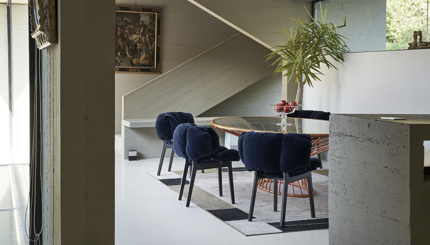 en groep Blue Velvet stoelen van Edra staat rond een moderne glazen eettafel. De diepe, zachte fluwelen bekleding en het ebbenhouten frame passen perfect in een eigentijds, stijlvol interieur.