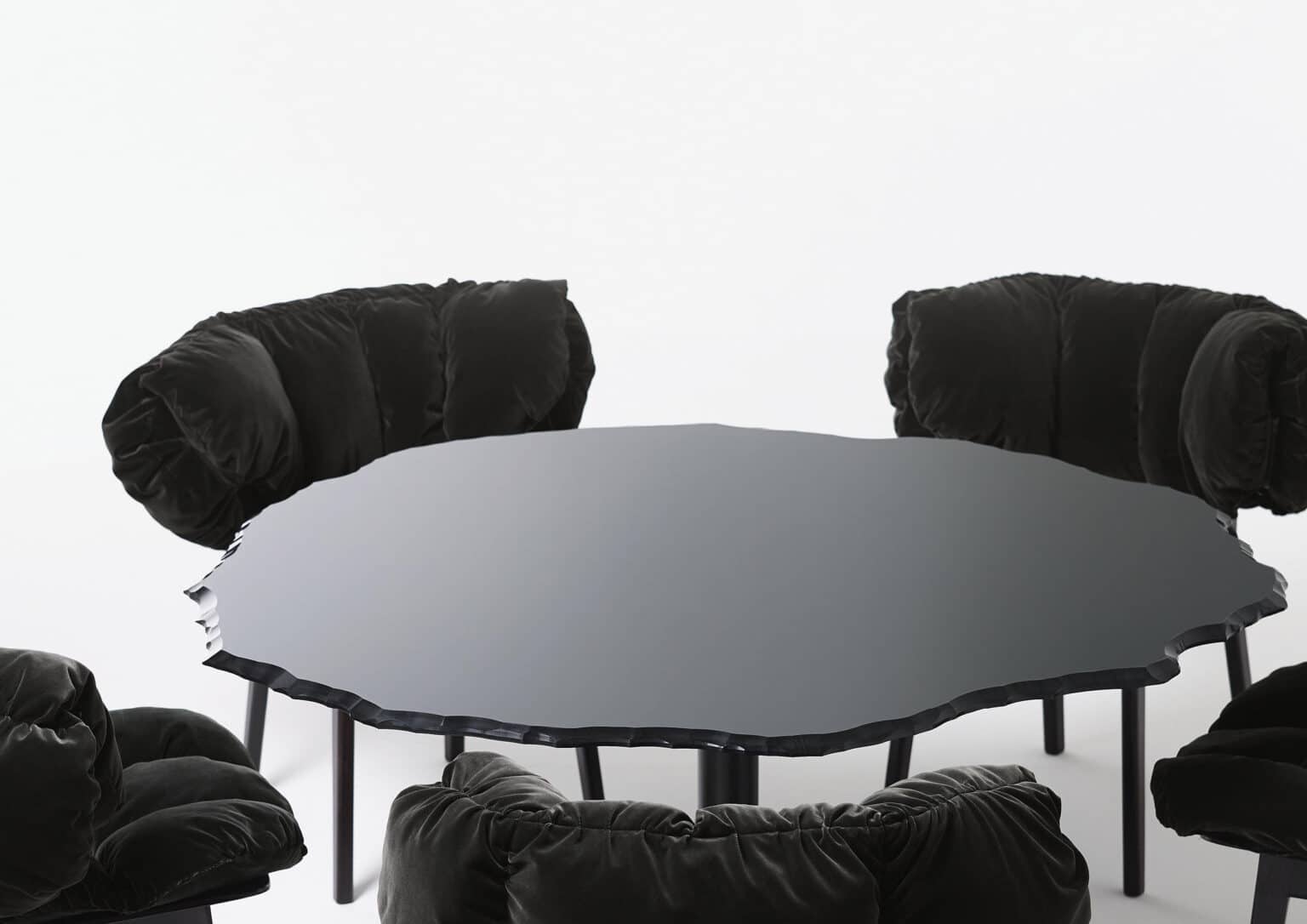 Deze afbeelding laat de Egeo Tafel van Edra zien in een ronde uitvoering, gecombineerd met luxueuze, zwarte stoelen die de tafel omringen. Het glazen tafelblad heeft een onregelmatige rand die de natuurlijke vormen van glas nabootst, wat het sculpturale karakter van het ontwerp versterkt. Het onderstel bestaat uit conische poten, die zorgen voor een stevige en stijlvolle basis. Deze setting benadrukt de veelzijdigheid van de Egeo Tafel en hoe het past in een moderne en verfijnde leefruimte.