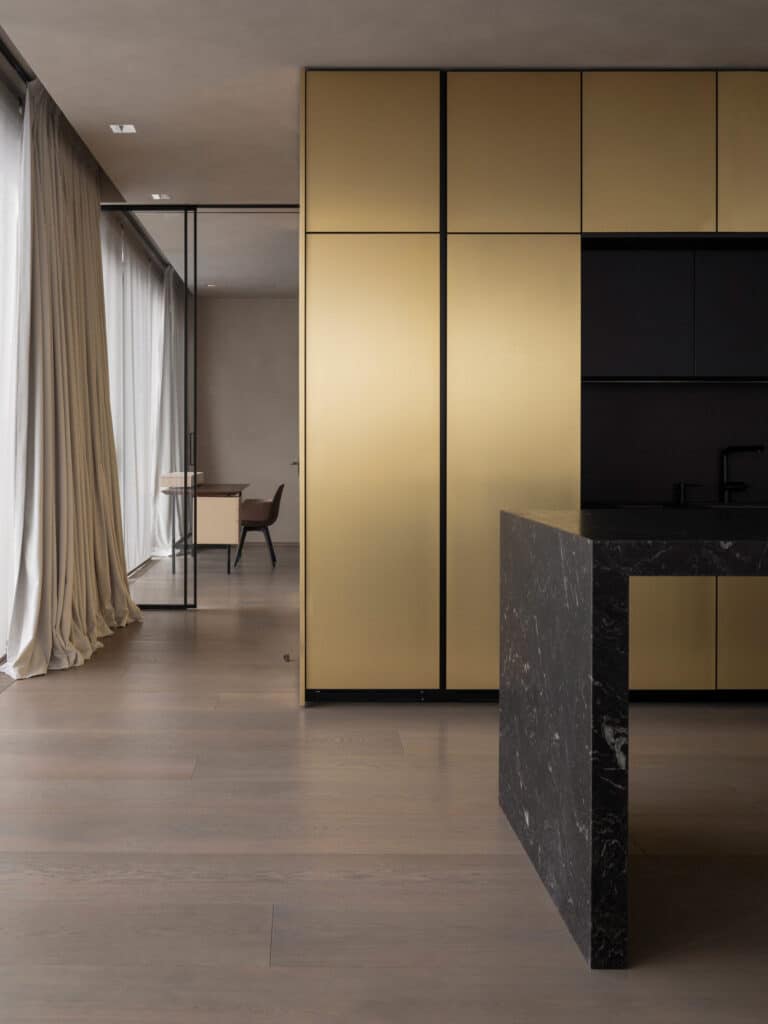 Moderne keuken met gouden kasten en een zwart marmeren keukeneiland, ontworpen met strakke lijnen en luxe materialen voor een verfijnde uitstraling – Italiaans architectonisch design