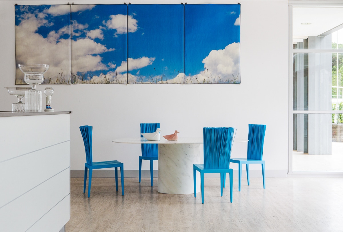 Een moderne eetkamer met blauwe Jenette-stoelen van Edra rond een marmeren tafel. De stoelen voegen een frisse en levendige touch toe aan het strakke interieur