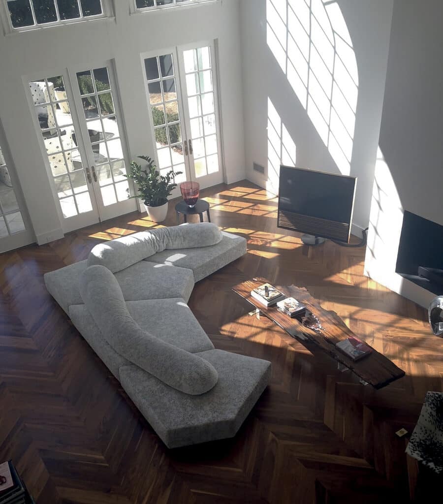 Moderne woonkamer met de Edra On the Rocks sofa in een open en lichte ruimte met houten visgraatvloer, grote ramen en een minimalistische inrichting – gefotografeerd bij daglicht voor een luxueuze uitstraling.