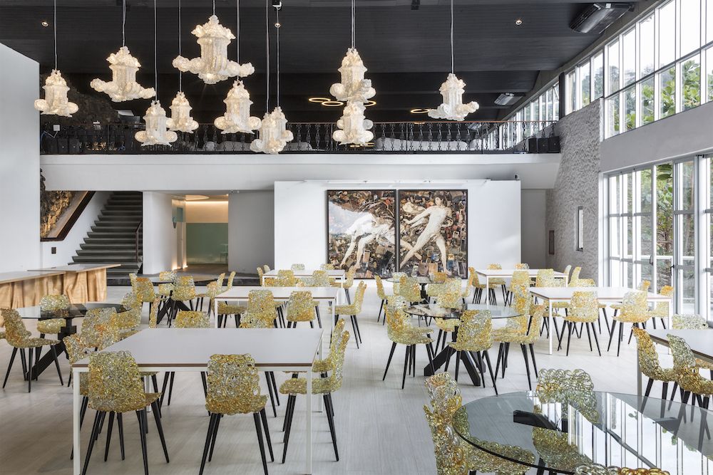 Een ruim en stijlvol restaurant waarin de Gina stoelen van Edra een speelse, moderne twist toevoegen aan de inrichting. De stoelen met amberkleurig polycarbonaat materiaal vullen de ruimte perfect aan onder de imposante kroonluchters, wat zorgt voor een chique en artistieke sfeer.